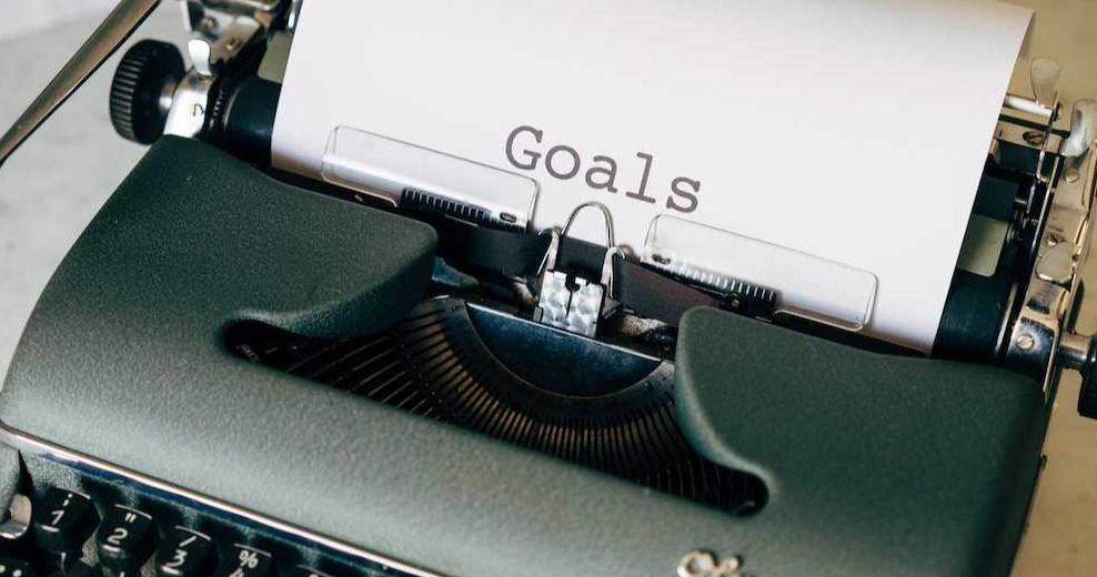 A dark green Olympia typewriter with a piece of paper that has had the word 'Goals' printed on it