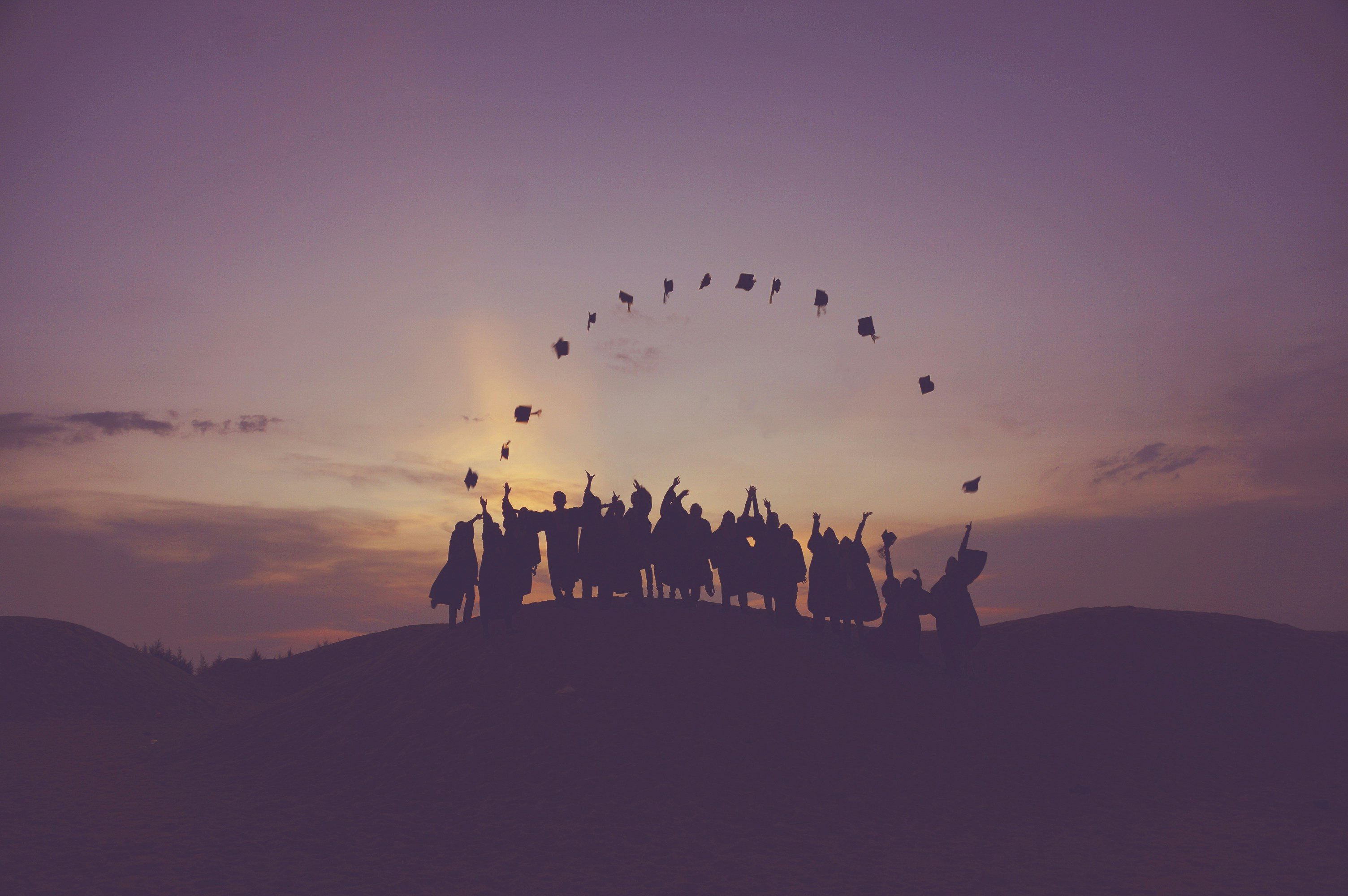 As group of graduates celebrating their achievement at sunset